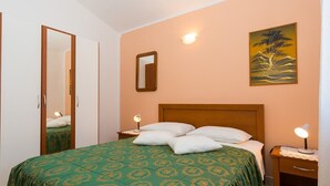 Une chambre à coucher comprenant un lit, une table de chevet, un miroir, une lampe fixée au mur et un tableau.
