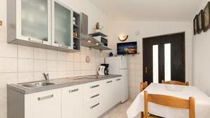Une cuisine moderne avec des meubles blancs, un évier en acier inoxydable et un coin repas comprenant une table et des chaises.