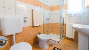 Une salle de bain comprenant des toilettes, un bidet, une douche et un lavabo.