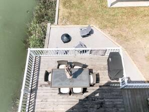 A wooden deck with a table and chairs, a grill, and a view of the water. - Renovated Island Cottage on OIB with views of Jinx Creek, 4 min walk to beach (Ocean Isle Beach)