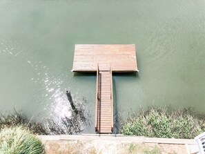 A wooden dock extending into a calm body of water, surrounded by grassy banks. - Renovated Island Cottage on OIB with views of Jinx Creek, 4 min walk to beach (Ocean Isle Beach)