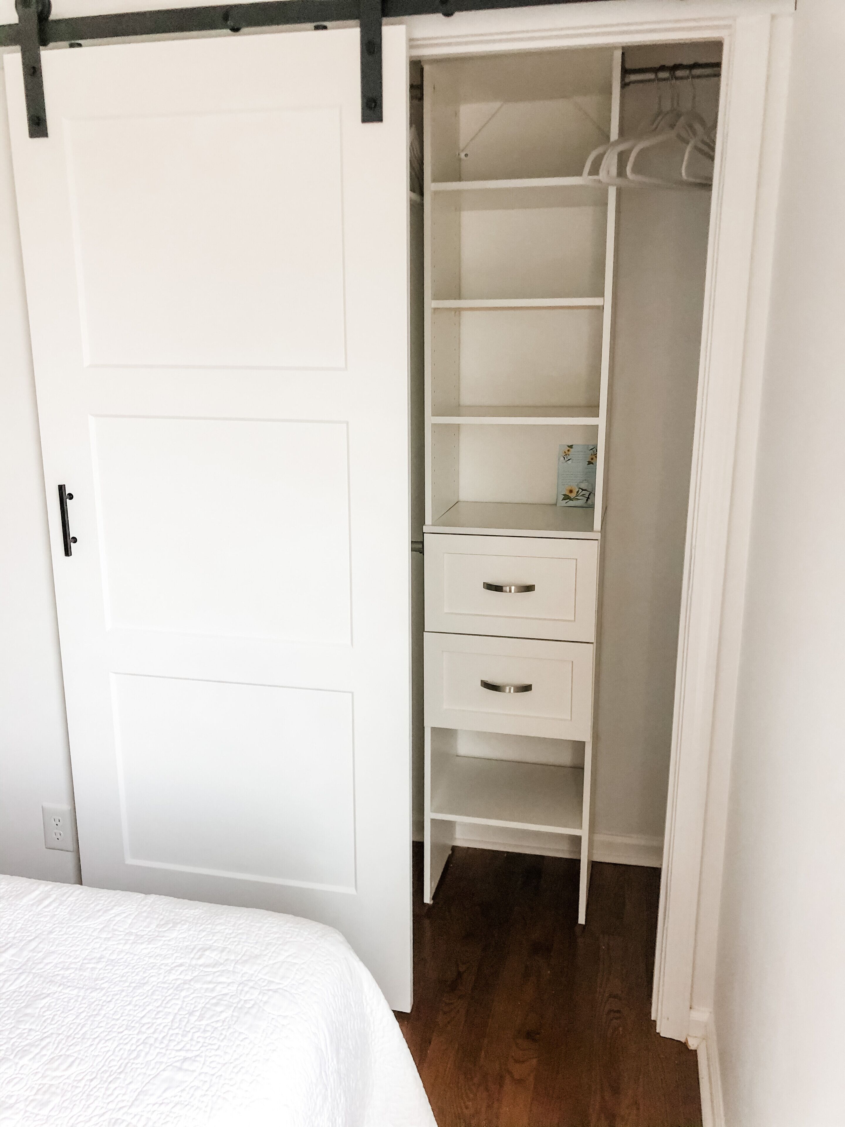 Un placard blanc, dont les portes sont ouvertes, laissant apparaître des étagères et un espace pour suspendre des vêtements.