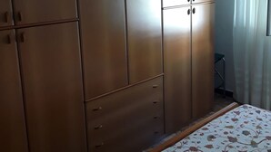Una camera da letto con un ampio armadio, un letto con copriletto floreale e una lampada a sospensione.