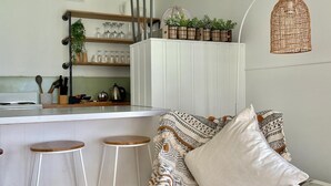Cocina moderna con armarios blancos, una barra con taburetes y un cojín estampado en una silla.