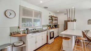 Una cocina moderna con armarios blancos, encimera de madera, horno empotrado y un taburete de bar.