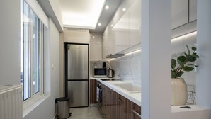 Eine moderne Küche mit Edelstahlkühlschrank, Mikrowelle und Backofen, Holzschränken und einem Fenster für natürliches Licht.