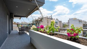 Ein Balkon mit Tisch und Stühlen, umgeben von Blumentöpfen und Blumen.