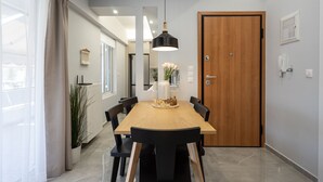 Ein Essbereich mit Holztisch, schwarzen Stühlen, einer hängenden Pendelleuchte und einer Holztür.