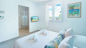 A hotel room with a bed, a TV, a shower, and a window with a view.