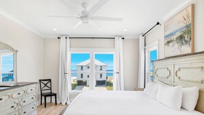 A bedroom with a large bed, a dresser, a chair, and a ceiling fan. - Luxury Coastal Retreat | Gulf Views | Private Elevator (Gulf Shores)