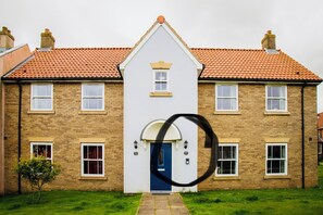 A two-story house with a blue door, multiple windows, and a red-tiled roof.