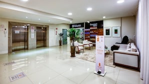 Un vestíbulo de hotel con una recepción, dos ascensores, una zona de estar con sillones y un cartel que dice 'Munn'.
