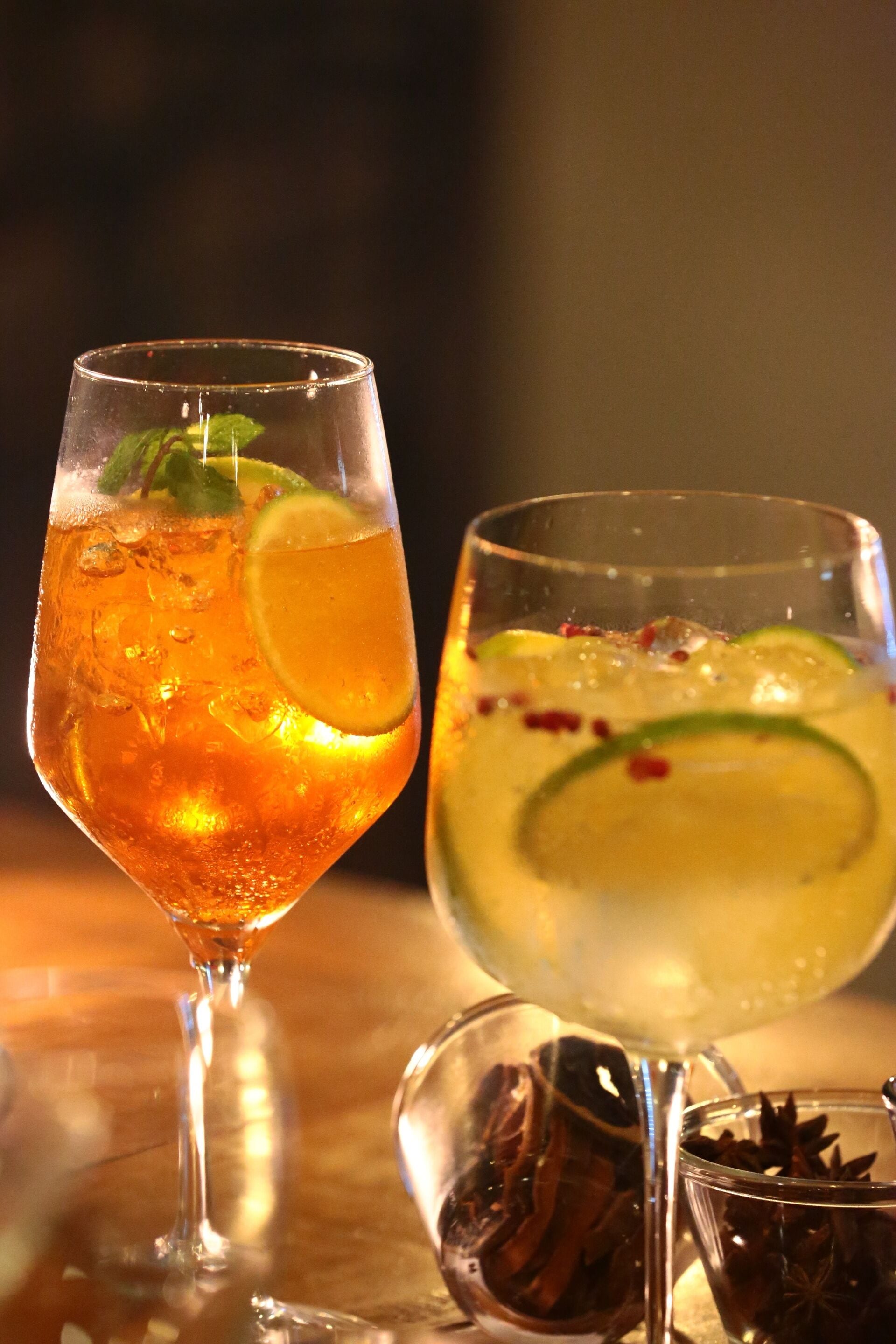 Duas bebidas em um copo sobre uma mesa, com fundo desfocado.