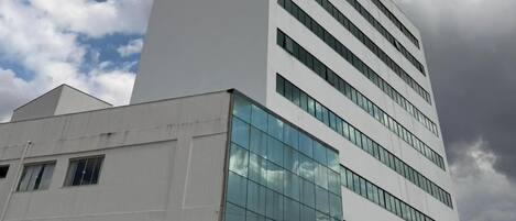 Un moderno edificio de hotel con un llamativo letrero 'fit', varios pisos y grandes ventanales que reflejan el cielo.