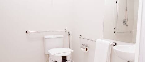 A modern bathroom with a white toilet, a sink, and a shower.