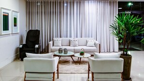 Una sala de estar moderna con un sofá blanco, dos sillones blancos, una silla negra, una mesa de centro y una planta en maceta.