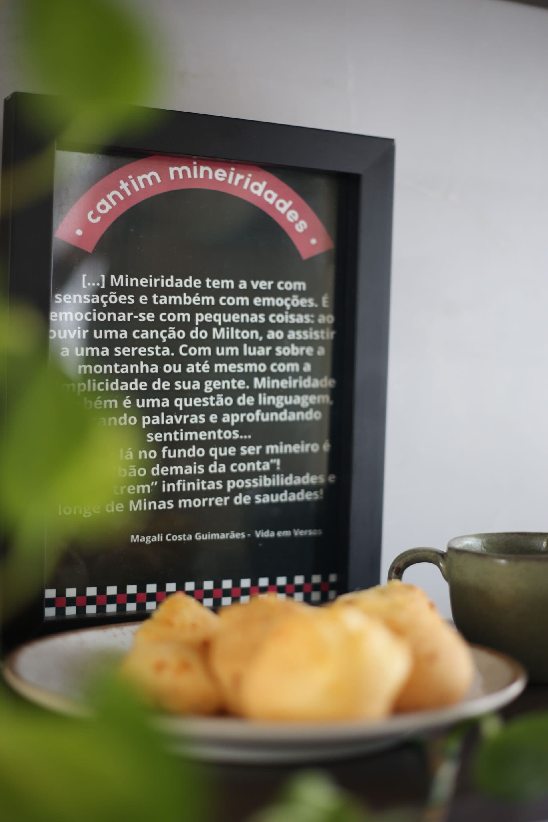 Una cita en marco sobre la identidad mineira, un plato de comida y una taza.