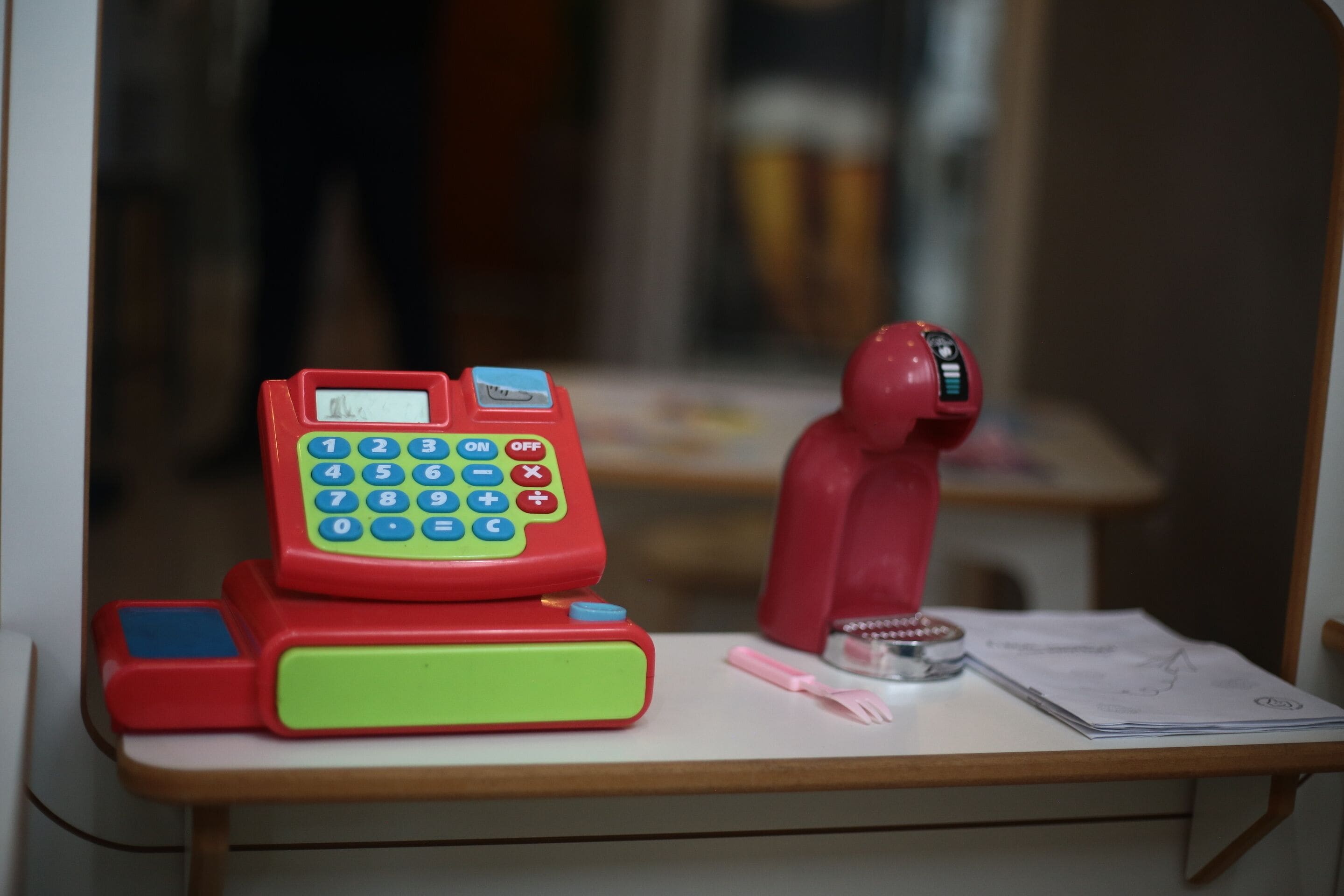 A toy telephone, calculator, and toy figure on a desk.