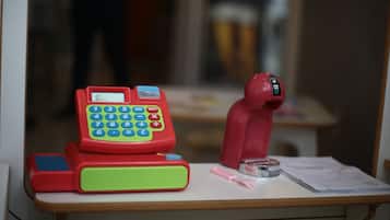 A toy telephone, calculator, and toy figure on a desk.