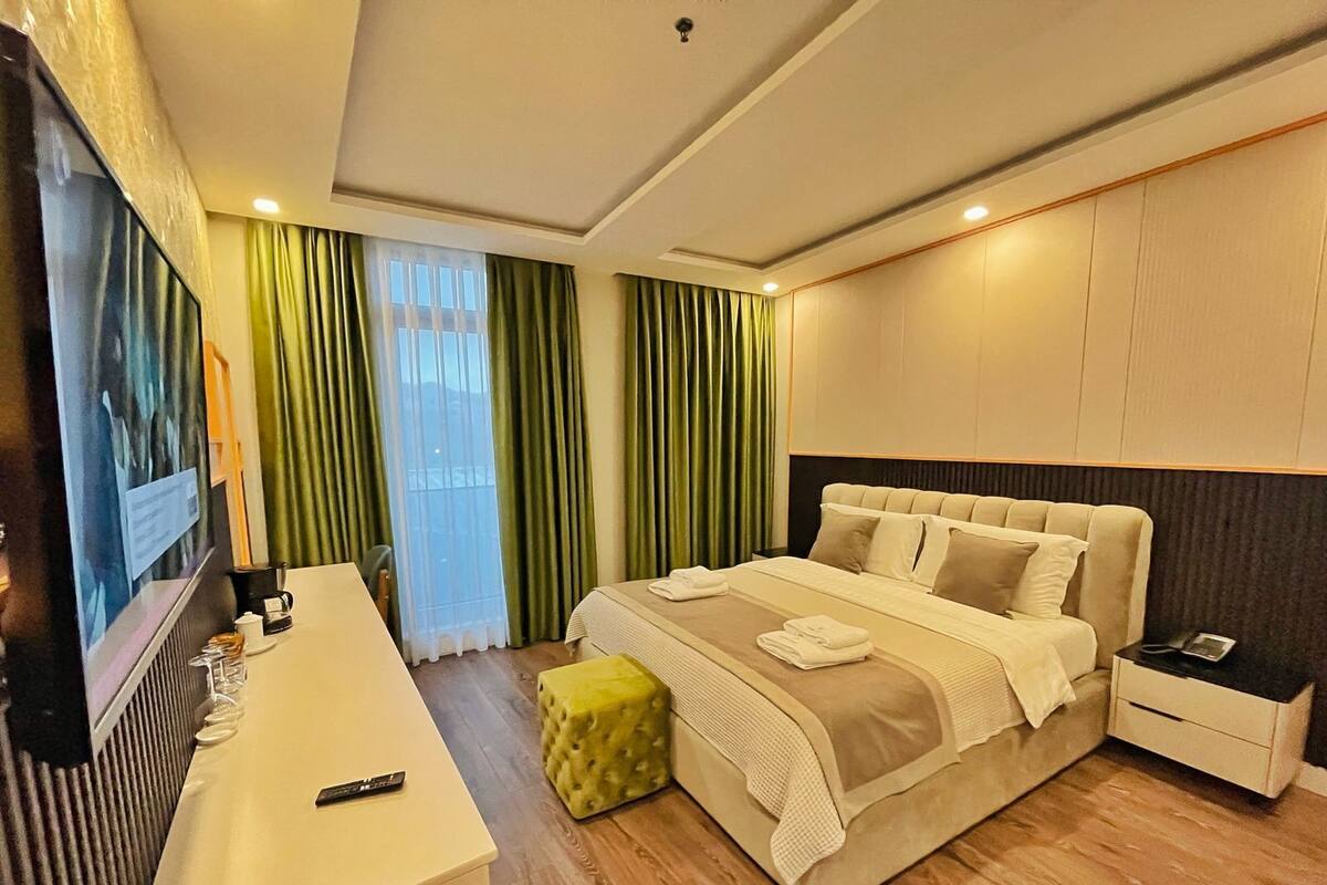 A hotel room with a bed, a TV, a desk, and a chair.