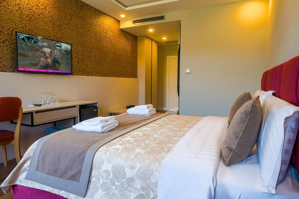 A hotel room with a bed, a desk, a television, and a shower area.