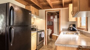 Eine Küche mit schwarzem Kühlschrank, Holzschränken, einer Arbeitsplatte aus Granit, einem Herd und einer Spüle.