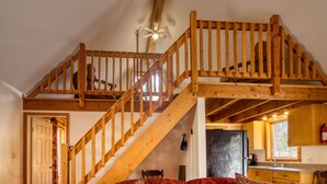 Eine Holztreppe führt zu einem Schlafzimmer auf dem Dachboden, ein Deckenventilator ist vorhanden.