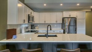 Una cocina moderna con armarios blancos, un refrigerador de acero inoxidable e una isla central con grifo negro.