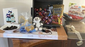 Et skrivebord med en æske forskelligt chokolade, en Kinder Bueno minichokoladebar, en Haribo Goldbears chokolade, en bamseabe og en skål med chokoladebolcher.