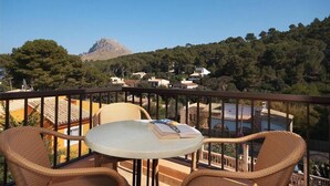 Ein Balkon mit Korbmöbeln und Blick auf einen Berg und Häuser.