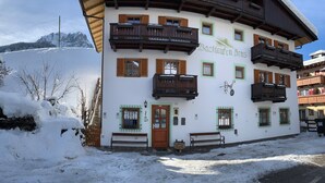 Ein traditionelles Chalet mit Holzbalkonen und einem mit Schnee bedeckten Dach.