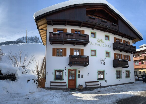 Un chalet traditionnel doté de plusieurs balcons, d’une façade en bois et d’une enseigne indiquant « Bachhaufen Haus ».
