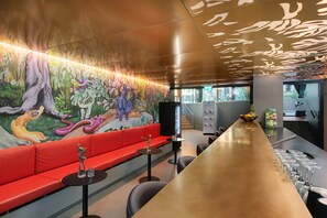A modern interior with a long counter, red seating, and a mural with colorful wildlife. - VISIONAPARTMENTS Basel Nauenstrasse (Basel)