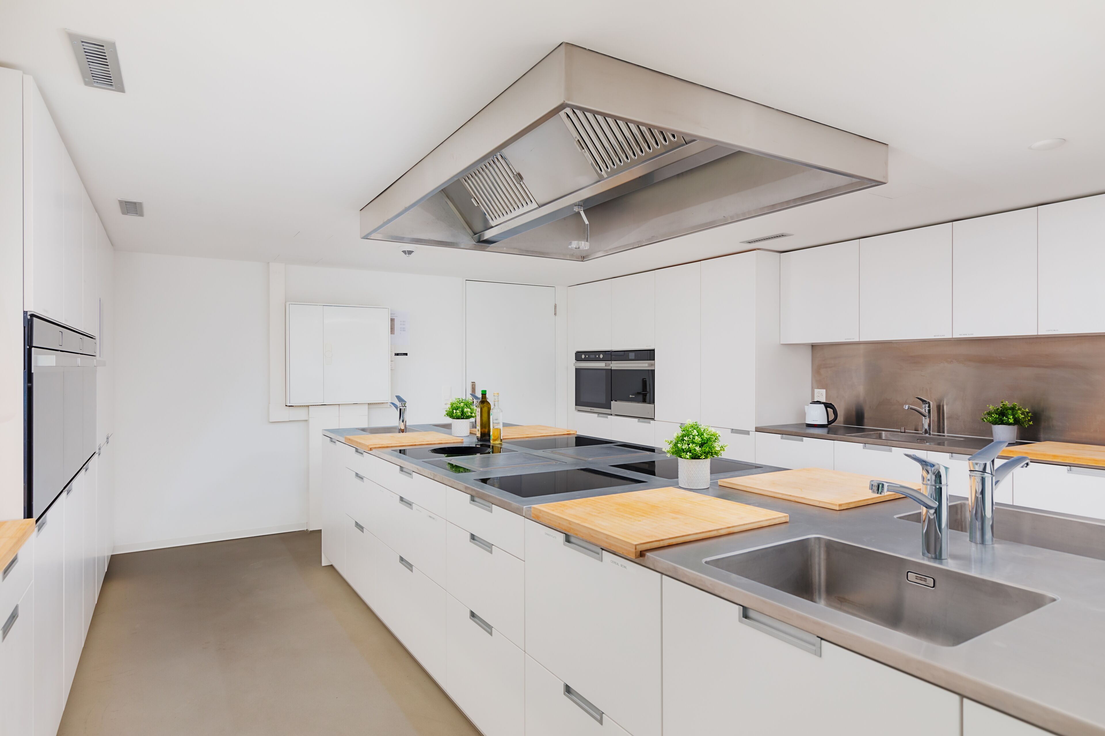 A modern kitchen with white cabinets, stainless steel appliances, and wooden countertops.