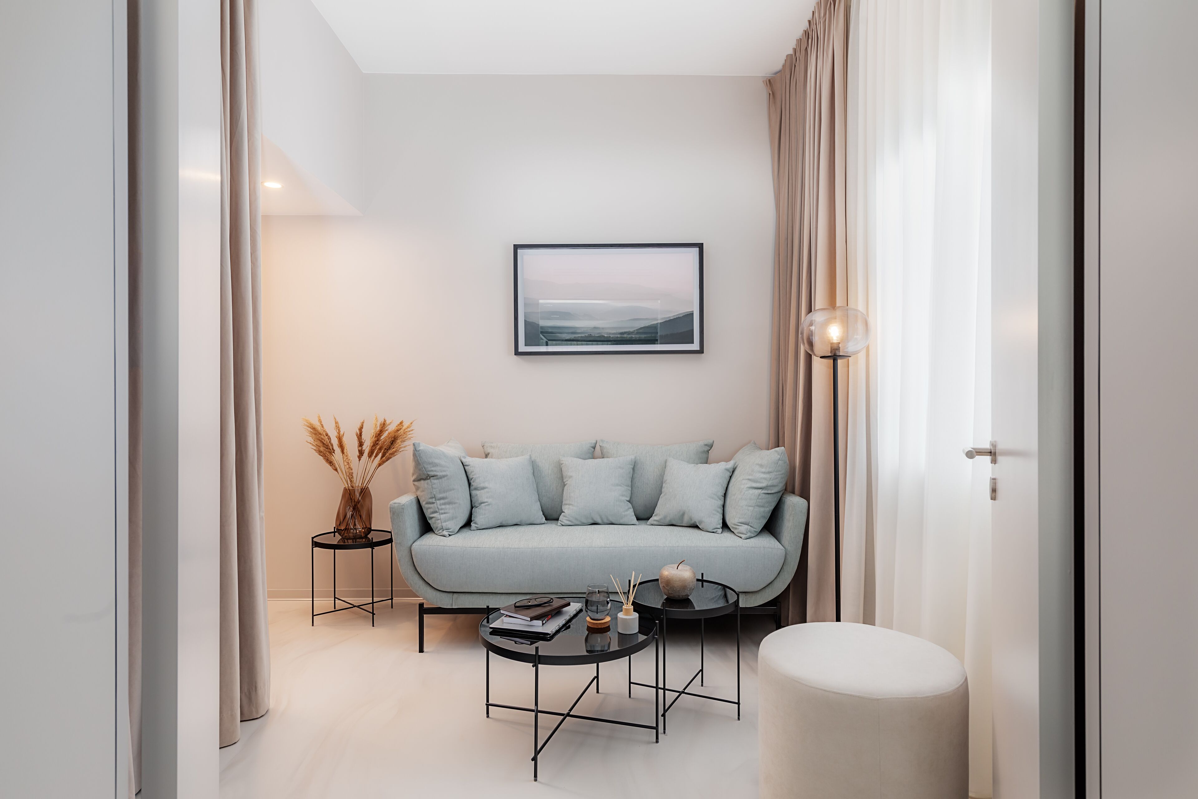 A modern living room with a light blue sofa, a round coffee table, and a framed picture on the wall.