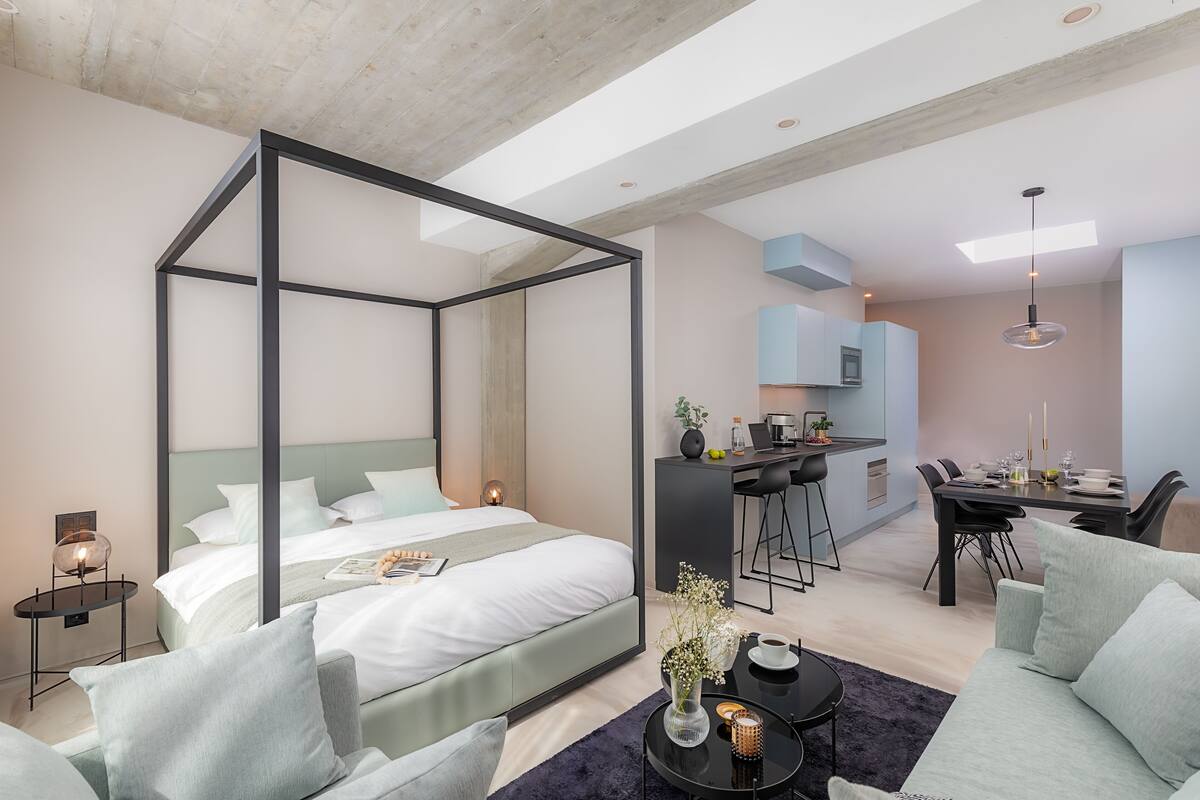 Et moderne hotelværelse med himmelseng, spiseplads og tekøkken.