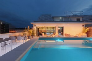 Un espace piscine sur le toit, avec des sièges extérieurs et un bar.