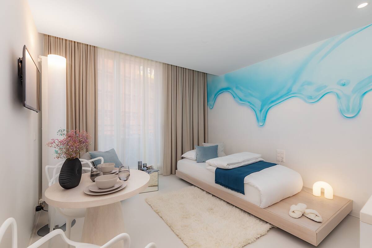 Et moderne hotelværelse med seng, natbord og et vægmaleri.