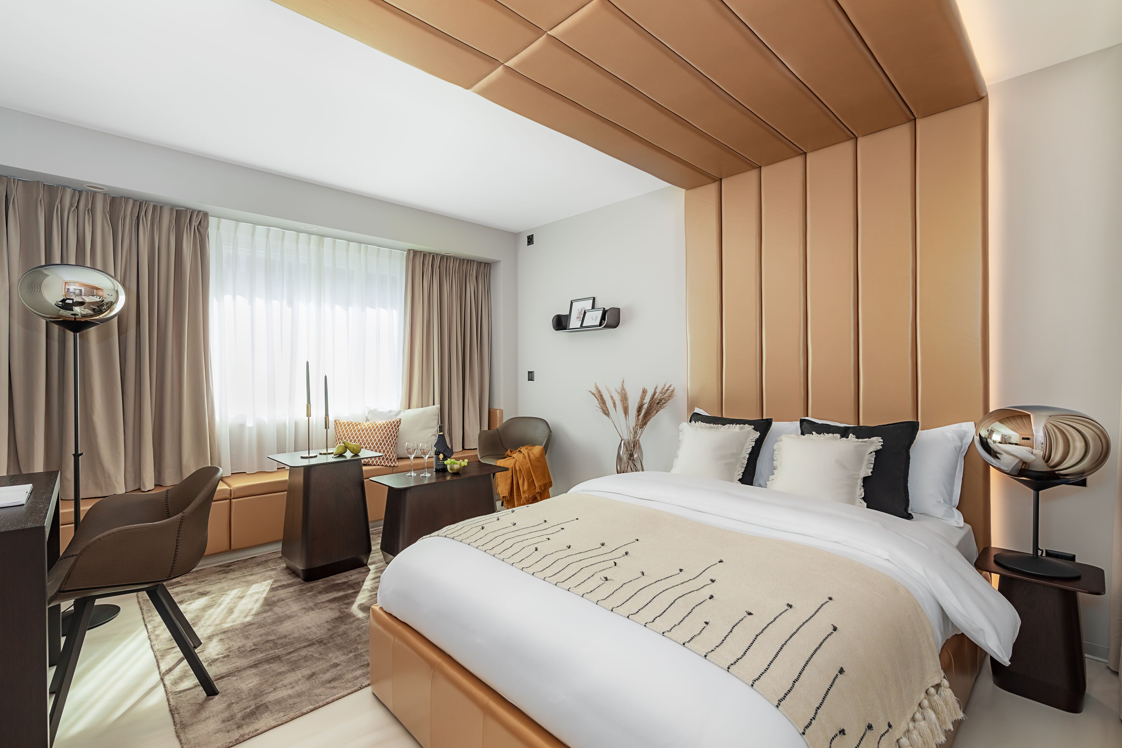 Una camera d'albergo moderna con un letto grande, una scrivania, una sedia e un comodino.