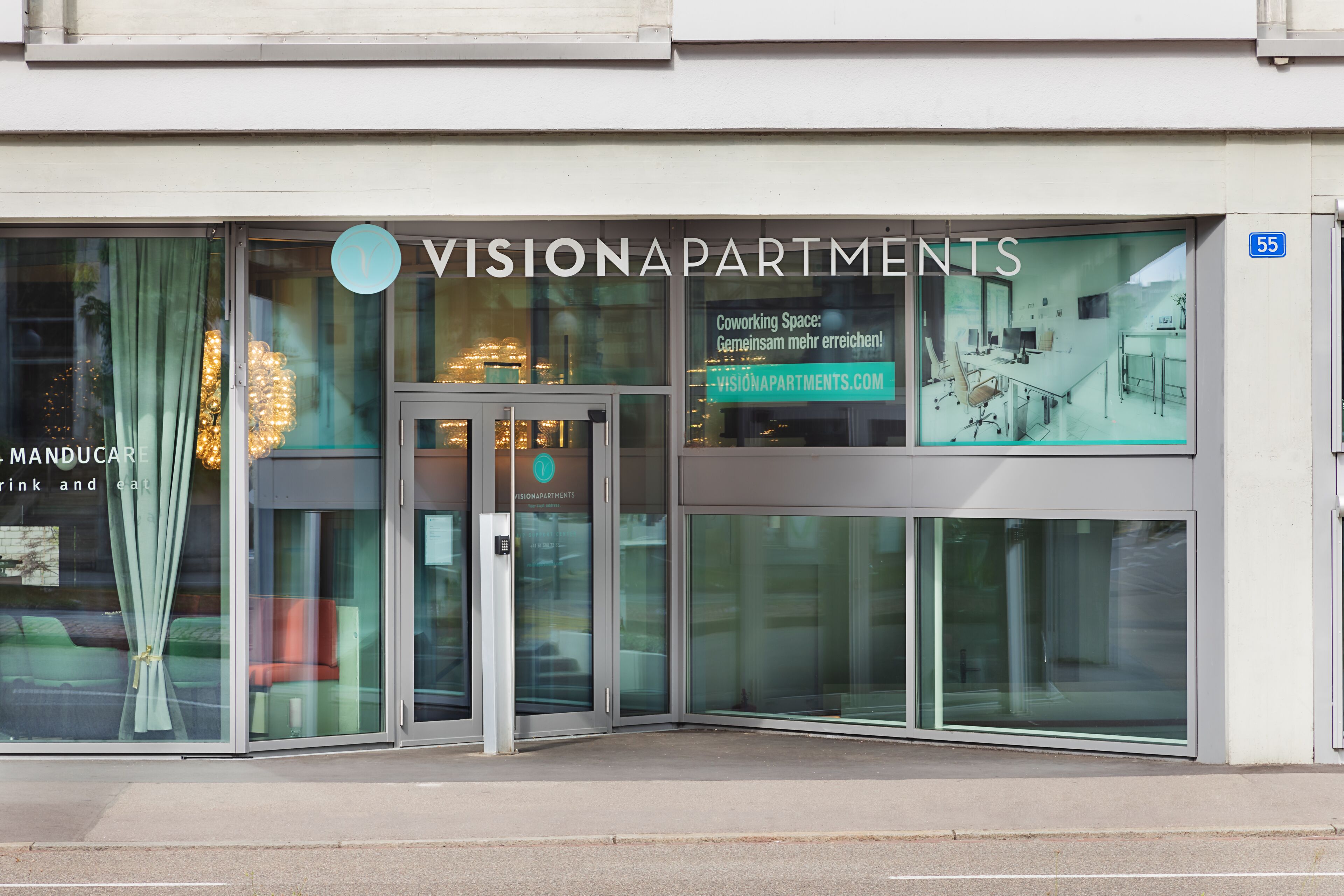 En moderne bygning med store glasfacader og et skilt for Vision Apartments.