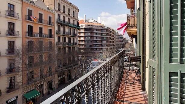 A balcony with a wrought iron railing overlooking a street with buildings. - Beautiful apartment to Enjoy the real Barcelona (Barcelona)