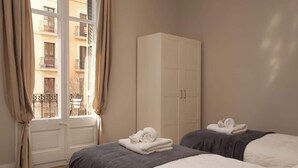 A hotel room with two beds, a wardrobe, and a window with curtains. - Beautiful apartment to Enjoy the real Barcelona (Barcelona)