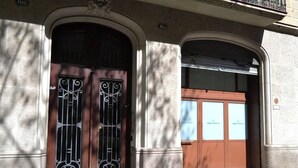 A building entrance with two large wooden doors, one with a metal gate, and a small balcony above. - Beautiful apartment to Enjoy the real Barcelona (Barcelona)