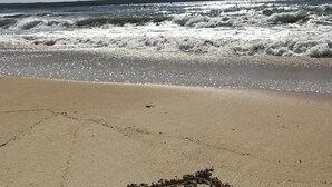 Une plage avec des vagues et un dessin réalisé dans le sable.