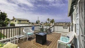 A wooden deck with wicker chairs, a table, and a fire pit. - Adorable Dog Friendly Vacation Home in Grover Beach (Grover Beach)