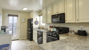A kitchen with white cabinets, a black microwave, a stove, and a toaster. - Adorable Dog Friendly Vacation Home in Grover Beach (Grover Beach)