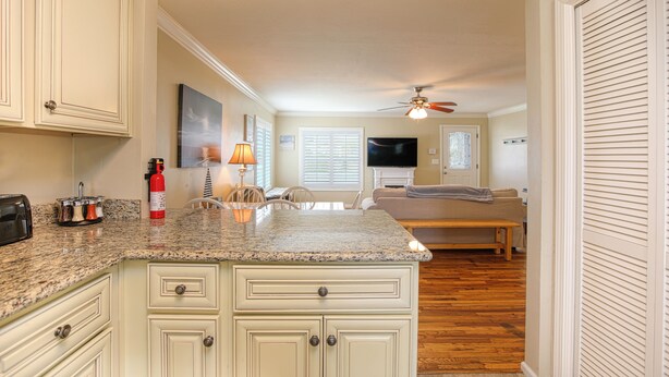 A kitchen with granite countertops, white cabinetry, a ceiling fan, and a dining area with a bench. - Adorable Dog Friendly Vacation Home in Grover Beach (Grover Beach)