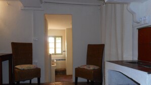 A room with two wicker chairs, a tiled floor, a white oven, and a doorway leading to a bathroom. - 80 m2 in a quiet, cool location, with double rooms, terrace and olive grove. (Aix-en-Provence)
