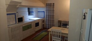 A compact kitchen with a built-in microwave, a small table, and a refrigerator.