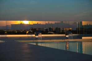 A rooftop pool with two water features and a city skyline in the background. - Salina Hotel (Taranto)